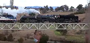 Restored steam locomotive no. 6029 hauling a load test train over the Queanbeyan River bridge