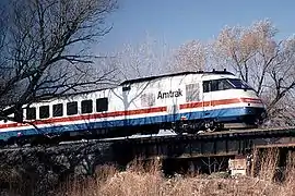 A white passenger trainset with red, white, and blue stripes of equal width on the side under the windows