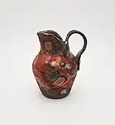 Made by Ruthann Hurwitz (The Village Potter) in the Western style of Raku. It was built with the coil and pinch method, glazed, then fired. It was removed from the 1800 degree kiln while red hot and placed into containers with combustibles, then covered where reduction takes place, "smoking" the pottery.