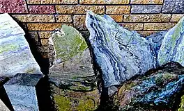 An image of some slabs of connemara marble against a wall. Each slab has coloured swirls, the middle one stands out because the entire slab is moss green in colour.