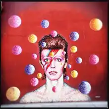 A painting of a man with red hair and a lightning bolt across his face surrounded by circles