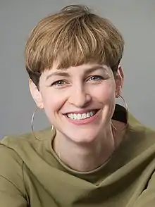 Natalie Grams wearing golden earrings, with a short haircut
