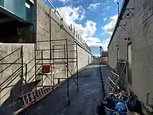 A ramp between a railway embankment and a single-story building