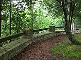 A trail in a forested area with a rock and wood wall.