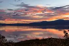 Image is taken at sunset with pinkish clouds, looking over the lake.