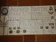 A tablet formed of five tiles of varying sizes, bordered by yellow and blue flowers in an art nouveau style