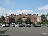A seven-story brick hospital building with a parking lot