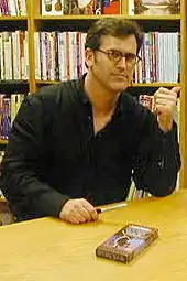 A man sitting at a table with a VHS on the table.