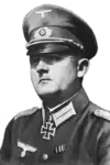 A man wearing a peaked cap and military uniform with an Iron Cross displayed at the front of his uniform collar.