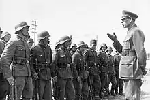 a black and white photograph of a bespectacled Andrey Vlasov in German uniform addressing some soldiers