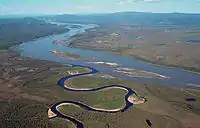 Aerial photo of the narrow horseshoe-bent Charley River flowing into the wide Yukon river with islands in the middle and nearby lakes