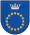 A coat of arms depicting a circle for which the boundary is itself made up of beige circles all under a silver crown on a blue background