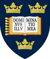 A shield displaying a coat of arms; on a dark blue background, an open book displays the words "Dominus illuminatio mea", with two gold crowns above and one below