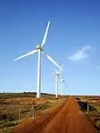 Wind turbines beside a red dirt road