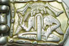 A buckle depicting a sitting man