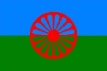 Flag of the Romani People. It contains blue and red colour to represent the heaven and earth respectively, and uses a 16 spoke Dharmachakra to symbolise their tradition and to pay homage to their Indian origin.