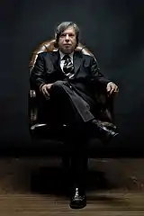 Portrait showing George Condo in a chair