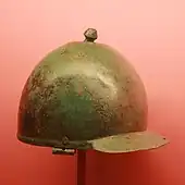 a photograph of an inverted, polished, slightly tarnished, battered bronze hemisphere