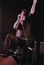 Man in black clothes and spiked hair performing vocals onstage