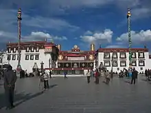 Ornate temple, with two poles and people in a courtyard