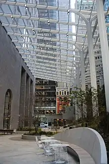 Southward view of 550 Madison Garden, the building's renovated atrium, in 2022.. The atrium has a glass roof. On the left is the building's facade, while on the right are benches and plants.