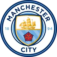A rounded badge depicting a shield containing a ship, the Lancashire Rose, and the three rivers of Manchester.