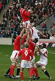 A Welsh player grasping the ball while being held in the air by his teammates following a line-out