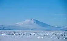  Distant view over an ice-covered sea of a conical mountain