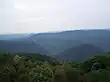 Forested green mountains viewed from a mountaintop.