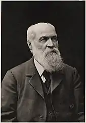 Head and shoulders of bald-headed, heavily bearded man looking to right