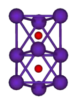 The ball-and-stick diagram shows two regular octahedra which are connected to each other by one face. All nine vertices of the structure are purple spheres representing rubidium, and at the centre of each octahedron is a small red sphere representing oxygen.