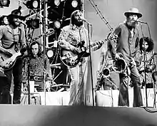 The Beach Boys performing on stage with an array of backup musicians. From the group, Al Jardine, Carl Wilson, and Mike Love are pictured.