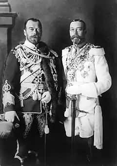 Two bearded men of identical height wear military dress uniforms emblazoned with medals and stand side-by-side