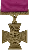 A bronze cross pattée bearing the crown of Saint Edward surmounted by a lion with the inscription 'FOR VALOUR'.  A crimson ribbon is attached.