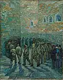 In an indoor prison yard a large group of men walk in a circle, one behind the other. The face of the prisoner in the centre of the painting and looking toward the viewer looks like Van Gogh.