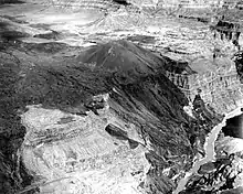 Dark-colored mass of rock draped over the side of a canyon