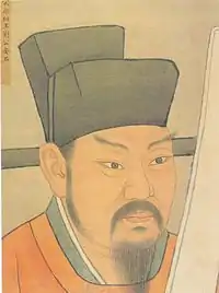 A head-shot style painting of a middle aged to late middle aged man with pointed eyebrows, sideburns, a mustache, and a beard. He is wearing a red robe and a black, square cut hat.