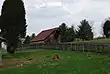 A wooden barn atop a lush green hill, with a wooden picket fence running through the center of the image.