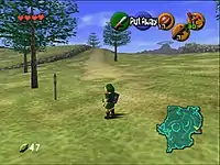 The child version of the game's protagonist, Link, stands in Hyrule field wearing his distinctive green tunic and pointed cap. In each corner of the screen are icons that display information to the player. In the upper left-hand corner, there are hearts, which represent Link's health, in the lower left-hand corner is a counter that displays the number of Rupees (the in-game currency) possessed by the player. There is a mini-map in the lower right-hand corner, and five icons in the upper right-hand corner, one green, one red, and three yellow, which represent the actions available to the player on the corresponding buttons of the N64 controller.