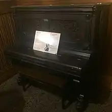 An old, black piano with a piece of paper on it.