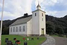 Wooden church with white horizontal panels and slate roof