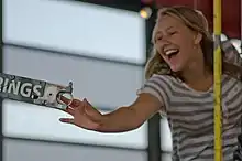 A woman riding a carousel, smiling as she grips a brass ring